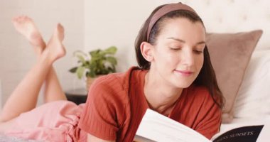 Kadın yatakta dinleniyor, kitap okuyor ve huzurlu bir öğleden sonranın tadını çıkarıyor. Rahatlama, rahatlama, sükunet, konfor, yaşam tarzı, konfor