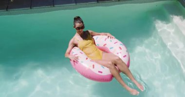 Havuzda dinlenirken, sarı mayo giymiş bir kadın pembe çörek arabasının keyfini çıkarıyor, fotokopi odası. Tatil, tatil, yaz, dinlenme, yüzme, havuz kenarı.