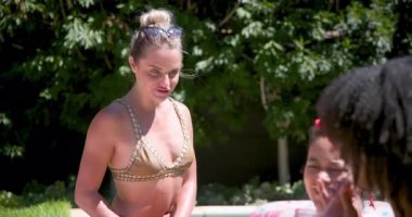 Çeşitli bayan arkadaşlar havuz başında gülerek ve içkiden zevk alarak yaz tatiline giriyorlar. Tatil, eğlence, arkadaşlık, açık hava, havuz kenarı, mutluluk.