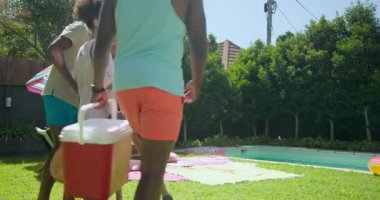 Çeşitli arkadaşlar havuz, serinlik ve havlularla piknik kurarak güneşli bir günün tadını çıkarıyorlar. Tatil, eğlence, arkadaşlık, yaz, rahatlama, dinlenme.