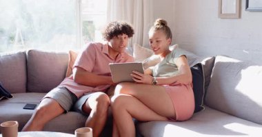 Kanepede dinlenen, tabletlerin keyfini çıkaran, mutlu çift, parlak oturma odasında, evde. Yaşam tarzı, rahatlık, rahatlama, teknoloji, bağlanma, birliktelik.