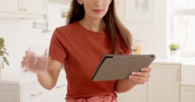 Mutfakta tablet kullanan, gülümseyen ve teknolojiden zevk alan bir kadın. Yaşam tarzı, mutluluk, bağlantı