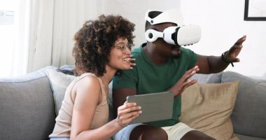 Kanepede, farklı arkadaşlar VR kulaklık kullanıyor, tabletli kadın evde birlikte gülüyor. Sanal gerçeklik, teknoloji, eğlence, eğlence, dijital, aygıt