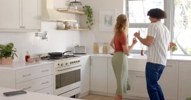 Parlak mutfakta dans eden mutlu çift, evde sabah rutininin tadını çıkarıyorlar. Dans, mutluluk, yaşam tarzı, ilişki, ev