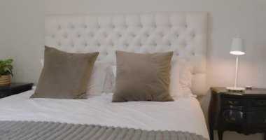 Zarif dekorlu rahat bir yatak odası, lüks yastıklar ve yatak başı lambası, evde. İç mekan, lüks, yatak, rahatlama, sükunet, mobilya.