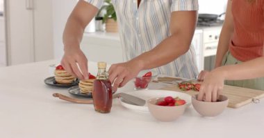 Çeşitli çiftler, modern mutfakta krep ve taze çilekle kahvaltı hazırlıyorlar. Yemek pişirme, aşçılık, brunch, birliktelik, yerli, sağlıklı beslenme.