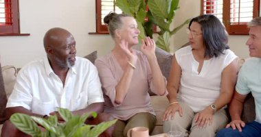 Kanepede oturan, gülen ve evdeki sohbetin tadını çıkaran farklı kıdemli arkadaşlar. Arkadaşlık, çeşitlilik, bağlılık, kahkaha, mutluluk, toplanma