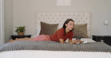 Evde dinleniyor, kadın yatakta kitap okuyor, boş vakitlerin tadını çıkarıyor. Rahatlama, yaşam tarzı, sükunet