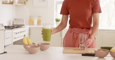 Modern mutfakta muz ve kaselerle taze yeşil meyve püresi hazırlıyorum. Sağlıklı, beslenme, detoks, blender, vegan, yemek