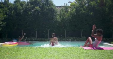 Çeşitli bayan arkadaşlar havuz başında güneşli bir günün tadını çıkarıyor, havluların üzerinde gülüyor ve dinleniyorlar. Tatil, tatil, rahatlama, güneşlenme, kahkaha, arkadaşlık.