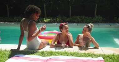 Çeşitli bayan arkadaşlar havuz başında dinleniyor, güneşli günlerin tadını çıkarıyor içkiler ve kahkahalarla. Boş zaman, tatil, yaz, havuz kenarı, rahatlama, kutlama