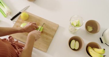 Sağlıklı meyve suyu hazırlamak için tahta tahtada yeşil elma dilimleyen bir kadın. Aşçılık, mutfak, meyve, sağlık, beslenme, aşçılık