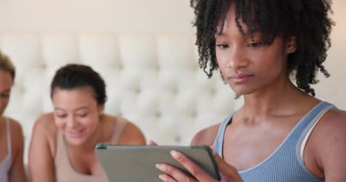 Çeşitli bayan arkadaşlar birlikte vakit geçiriyorlar, gülümsüyorlar ve yataktaki tablete bakıyorlar. Arkadaşlık, teknoloji, eğlence, dijital, rahatlama, yaşam tarzı