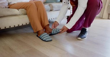 Bakıcı yaşlı bir kadınla el ele tutuşuyor, evde sıcak sohbetler ediyor. Bakım, arkadaşlık, destek, bağlantı, yerli, etkileşim