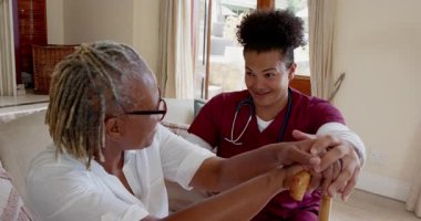 Bakıcı ve yaşlı kişi evinde neşeli anlar paylaşıyor, sıcak bir şekilde gülümsüyor. Bakım, yaşlılık bakımı, arkadaşlık, destek, sağlık, sıcaklık