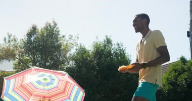 Çeşitli arkadaşlar renkli şemsiyeli, neşeli ve rahatlatıcı havuz başında güneşli bir günün tadını çıkarıyorlar. Tatil, tatil, yaz, rahatlama, arkadaşlık, açık hava.