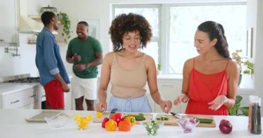 Çeşitli arkadaşlar mutfakta renkli sebzeler hazırlıyor, evde birlikte yemek pişiriyorlar. Mutfak, sağlıklı beslenme, yaşam tarzı, yerli, takım çalışması, sosyal