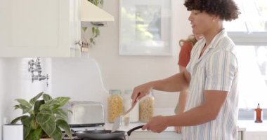 Young diverse couple cooking together in bright kitchen, smiling and enjoying moment, at home. Culinary, togetherness, romantic, bonding, affection, happiness