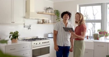 Çeşitli çiftler mutfak yenileme planlarını tartışıyor, evde tasarım fikirleri için tablet kullanıyorlar. ev geliştirme, iç tasarım, teknoloji, tadilat, beyin fırtınası, işbirliği