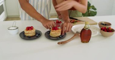 Çeşitli çiftler, modern mutfakta taze çilekli lezzetli krepler hazırlıyorlar. Yemek, kahvaltı, aşçılık, gastronomi, lezzet, malzemeler.