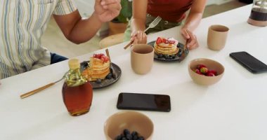 Çeşitli çiftler kahvaltıda krep ve böğürtlen yiyor..