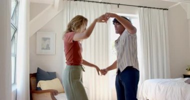 Çeşitli çiftler evde neşeyle dans ediyor, birlikte neşeli ve eğlenceli bir an geçiriyorlar. Dans, kutlama, mutluluk, hareket, müzik, eş