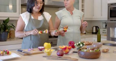 Modern mutfakta taze sebzeler hazırlayan, evde yemek pişirmekten hoşlanan iki farklı son sınıf öğrencisi kadın. Aşçılık, dostluk, yerli, gurme, hazırlık, takım çalışması