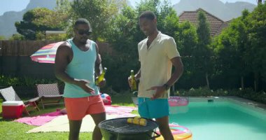 Çeşitli arkadaşlar bilardo oynarken, güneşli bir günde mısır kızartırken. Yaz, barbekü, havuz başı, rahatlama, açık hava yemeği, boş zaman.