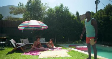 Çeşitli arkadaşlar havuz başında güneşli bir günün tadını çıkarıyorlar, havlularla oynayıp dinleniyorlar. Tatil, tatil, yaz, rahatlama, dinlenme, arkadaşlık.