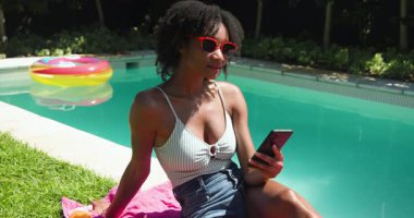 Güneş gözlüklü bir kadın havuz başında selfie çekiyor açık havada güneşli bir günün tadını çıkarıyor, fotokopi çekiyor. Yaz, tatil, rahatlama, tatil, yaşam tarzı.