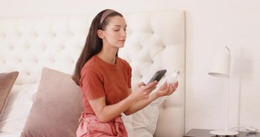 Yatak odasında rahat bir şekilde yatarken komodindeki lambayı ayarlayan kadın. Rahatlama, iç mekan, ev, mobilya, ışıklandırma, yaşam tarzı