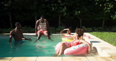 Farklı arkadaşlar renkli havuz kenarlarında dinleniyor, güneşli bir günün tadını çıkarıyorlar. Tatil, yaz, tatil, rahatlama, yüzme, havuz kenarı