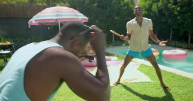 Çeşitli arkadaşlar renkli şemsiyeler altında havuz başında rahatlıyor, güneşli günün tadını çıkarıyorlar. Tatil, dinlenme, tatil, yaz tatili, arkadaşlık, açık hava