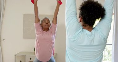 Evde bakıcının rehberliğinde direniş bandıyla egzersiz yapan yaşlı bir kadın. Yaşlılık, fitness, bakım, egzersiz, sağlık, direniş eğitimi