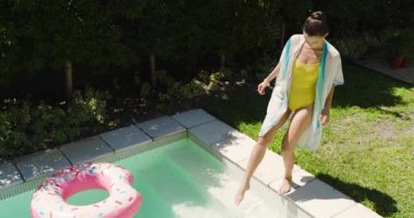 Sarı mayo giymiş bir kadın havuza giriyor, açık havada güneşli bir günün tadını çıkarıyor. Yüzme, yaz, dinlenme, dinlenme, dinlenme, tatil