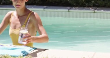 Havuzda dinlenen, güneşli günlerin tadını çıkaran bir kadın, ferahlatıcı bir içecekle birlikte. Rahatlama, rahatlama, yaz, tatil, havuz kenarı, içecek.
