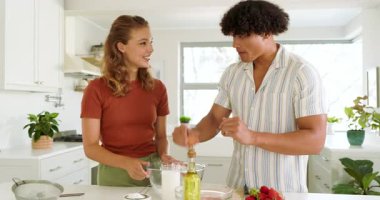 Çeşitli çiftler gülerken, evlerinde, parlak mutfakta kaseye yumurta kırıyorlar. Pişirme, pişirme, kahkaha, ilişki, hazırlık, ev