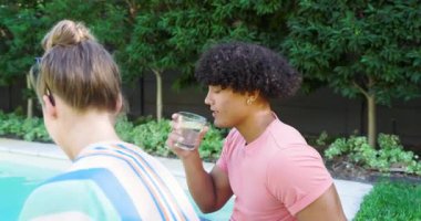 Çeşitli çiftler havuz başında rahatlıyor, içkinin tadını çıkarıyor ve dışarıda keyifli sohbetler ediyorlar. Tatil, dinlenme, tatil, yaz, havuz başı, tropik