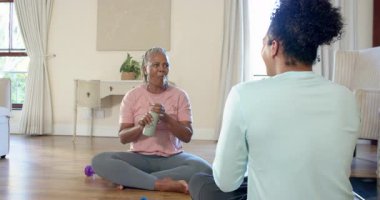 Üst düzey bir kadın bakıcı ile yerde oturuyor, gülümsüyor ve evde konuşmaktan zevk alıyor. Yaşlılar, bakıcılar, yoldaşlar, aile içi, destek, mutluluk.