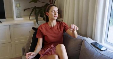 Kanepede dinlenen gülümseyen kadın evde akıllı telefon kullanıyor, boş zamanların tadını çıkarıyor. Teknoloji, rahatlama, iletişim, rahatlık