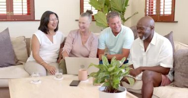 Üst düzey çeşitli arkadaşlar evdeki rahat oturma odasında dizüstü bilgisayarın etrafında gülüp tartışıyorlar. Yaşlılar, dostluk, teknoloji, eğlence, mutluluk, tartışma