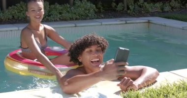 Çeşitli çiftler bilardo oynuyorlar, gülümsüyorlar ve akıllı telefonlarıyla selfie çekiyorlar. Tatil, seyahat, teknoloji, eğlence, havuz kenarı, rahatlama.