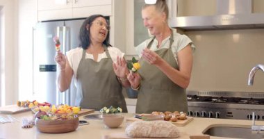 Modern mutfakta taze sebzeler hazırlayan, evde yemek pişirmekten hoşlanan kıdemli kadınlar. Arkadaşlık, aşçılık, hazırlık, kıdemli yetişkinler, yaşam tarzı