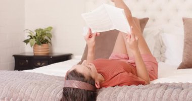 Evde dinleniyor, kadın yatakta kitap okuyor, boş vakitlerin tadını çıkarıyor. Yaşam tarzı, rahatlık, rahatlık, rahatlık.