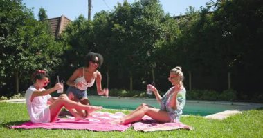 Çeşitli bayan arkadaşlar güneş gözlüğü takarak güneşli bir günde havuz başında içki içip dans ediyorlar. Parti, kutlama, yaz, tatil, rahatlama, dinlenme