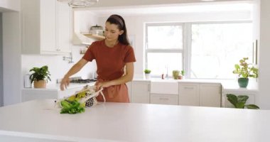 Parlak mutfakta meyve ve sebzelerle çevrili taze salata hazırlayan bir kadın. Sağlıklı, yaşam tarzı, yemek pişirme, beslenme, aşçılık, sağlık