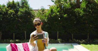 Bilardoda dinlenen, güneş gözlüklü, içki içen, akıllı telefon kullanan, fotokopi çeken bir kadın. Tatil, tatil, güneşlenme, dinlenme, teknoloji.