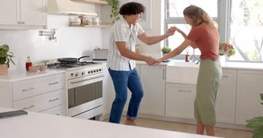 Modern mutfakta, evde, akıllı telefonlara bakarken çeşitli çiftler birlikte gülüyor. Teknoloji, mutluluk, birliktelik, bağlantı, yaşam tarzı, yemek