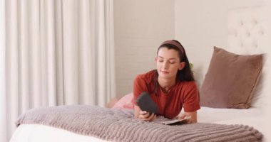 Yatakta dinlenen, kitap okuyan ve huzurlu bir öğleden sonranın tadını çıkaran genç bir kadın. Rahatlama, rahatlama, edebiyat, sükunet, konfor, huzur