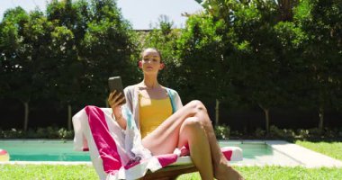 Kadın havuzda dinleniyor, selfie çekiyor ve güneşli bir günde ferahlatıcı içkinin tadını çıkarıyor, fotokopi çekiyor. Tatil, tatil, yaz, rahatlama, akıllı telefon, içecek.